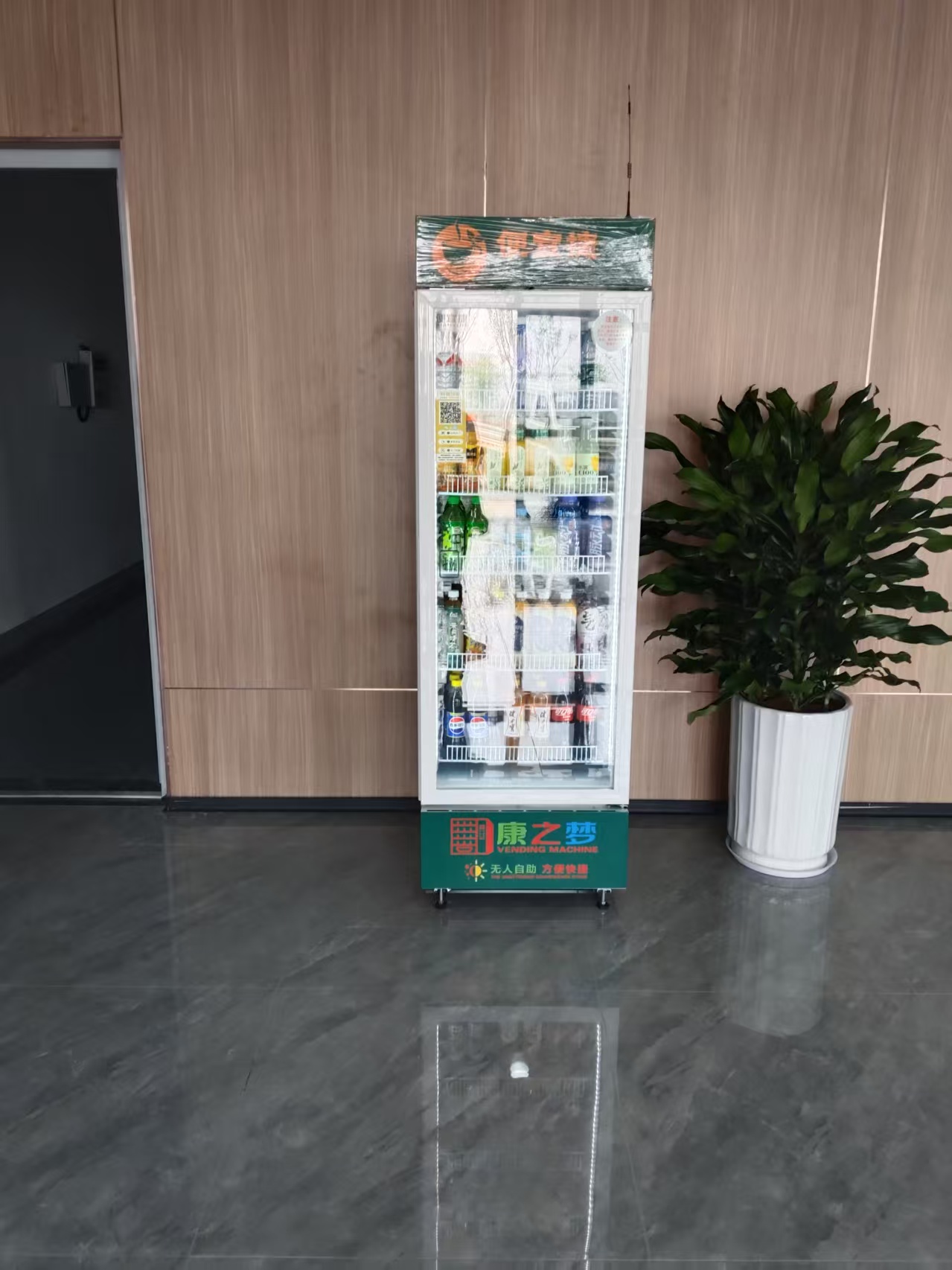 办公大楼大堂场景,智能售货机放置在休息区,员工正在使用,现代化办公环境